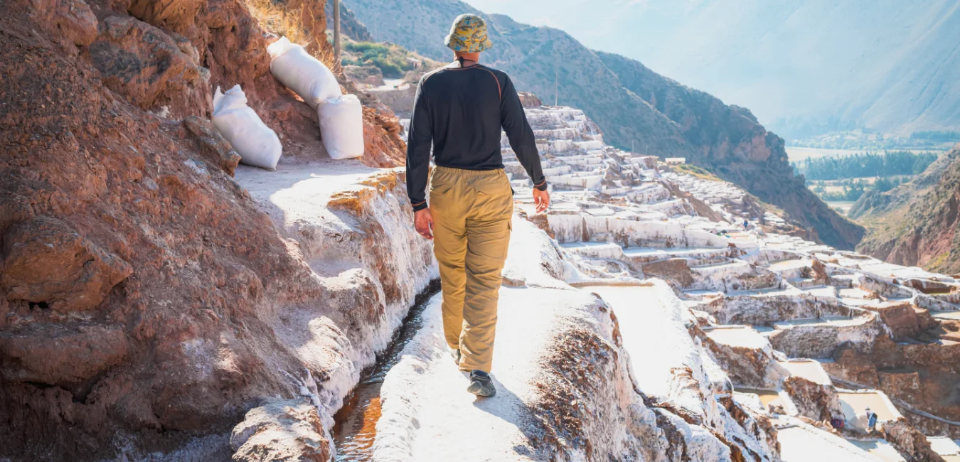Tourist walking among the salt ponds at Maras