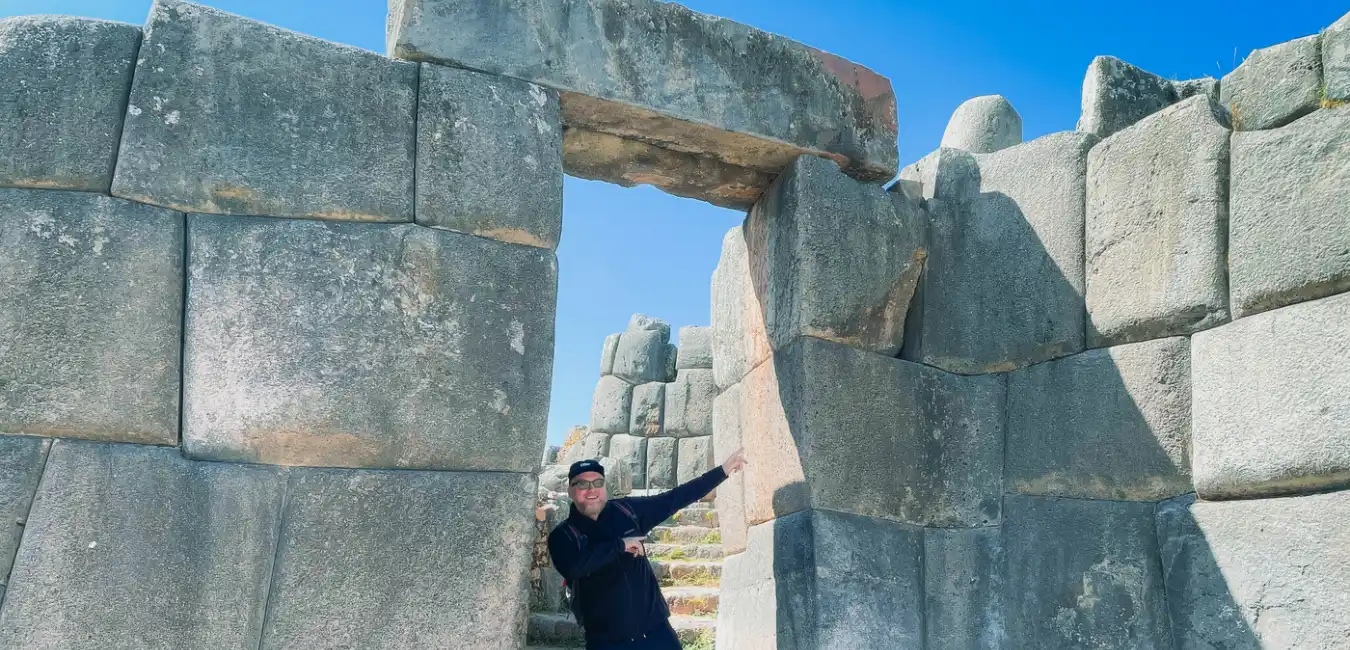 Traveler posing at an ancient Inca stone gateway on a Cusco City Tour